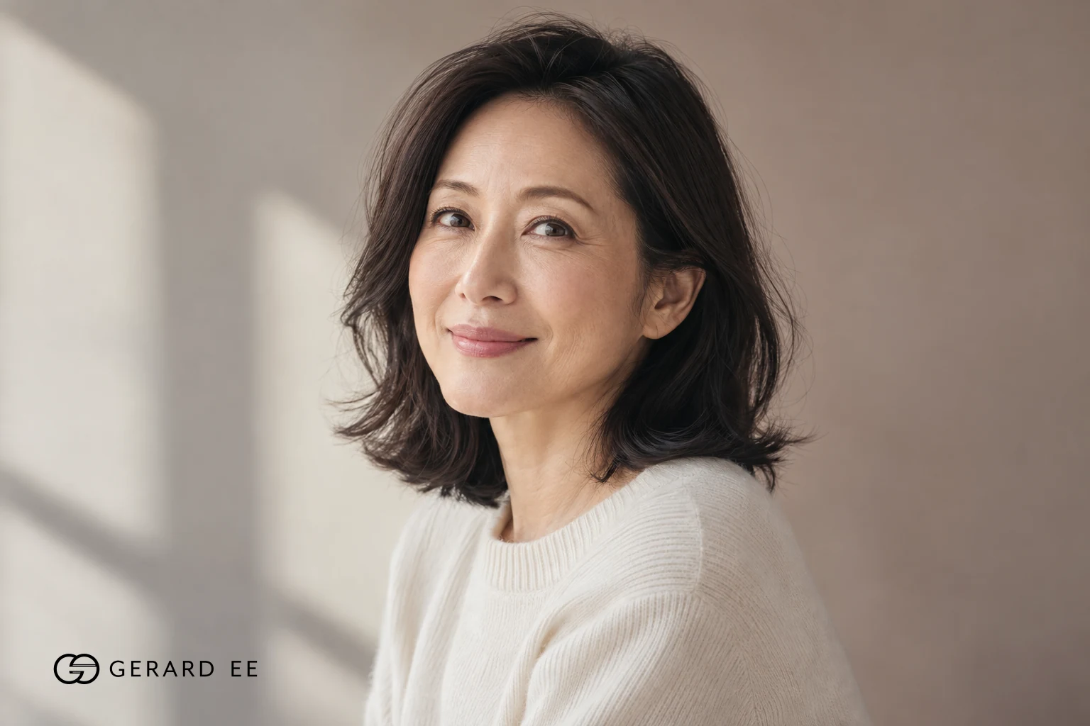 Woman in her forties photographed in natural light against a neutral wall