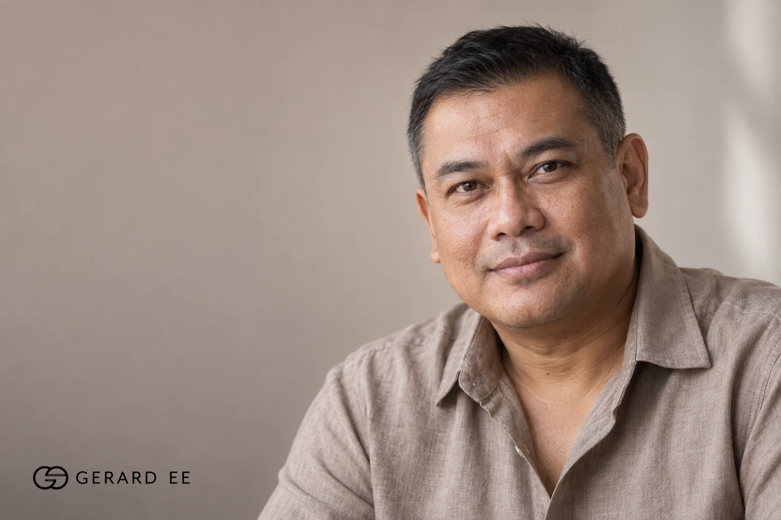 Man with greying hair in a brown linen shirt, photographed in soft natural light