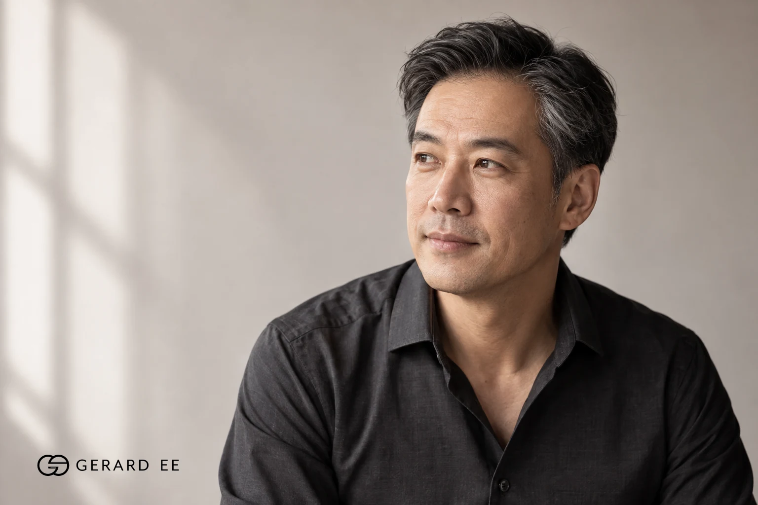 Man in his fifties with grey hair, photographed in natural light against a neutral wall